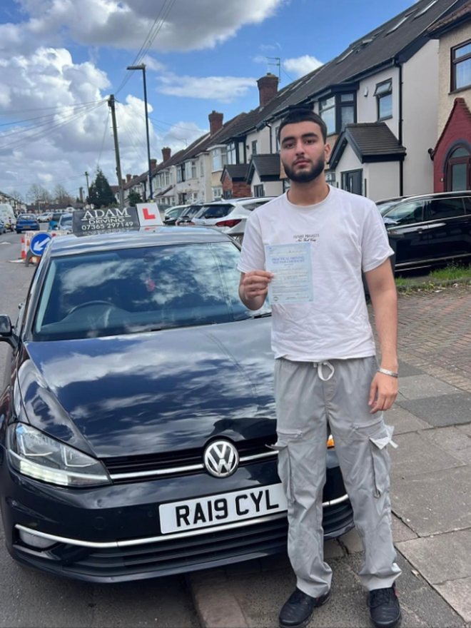 Student holding their driving test pass certificate beside the Adam Driving School car