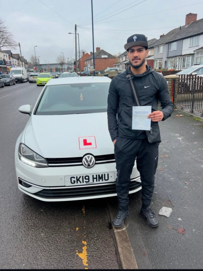 Student holding their driving test pass certificate beside the Adam Driving School car