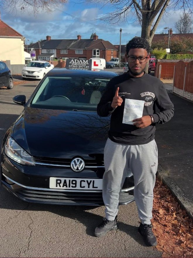 Student holding their driving test pass certificate beside the Adam Driving School car