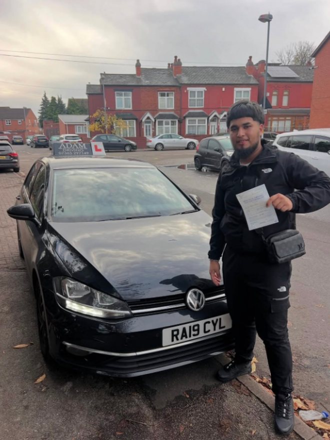 Student holding their driving test pass certificate beside the Adam Driving School car