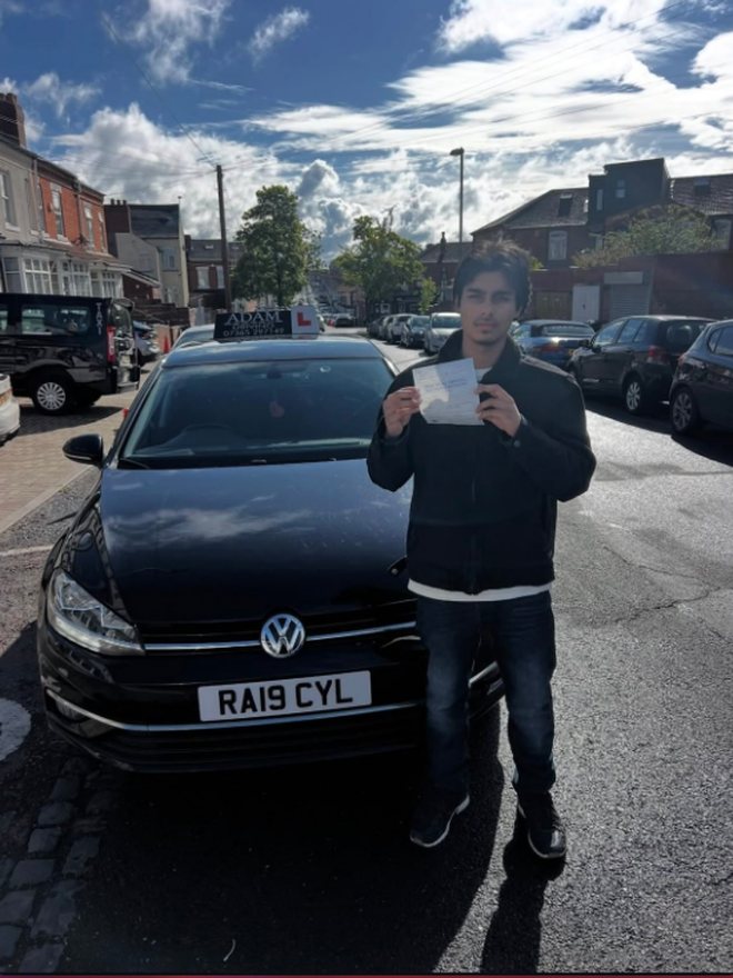 Student holding their driving test pass certificate beside the Adam Driving School car