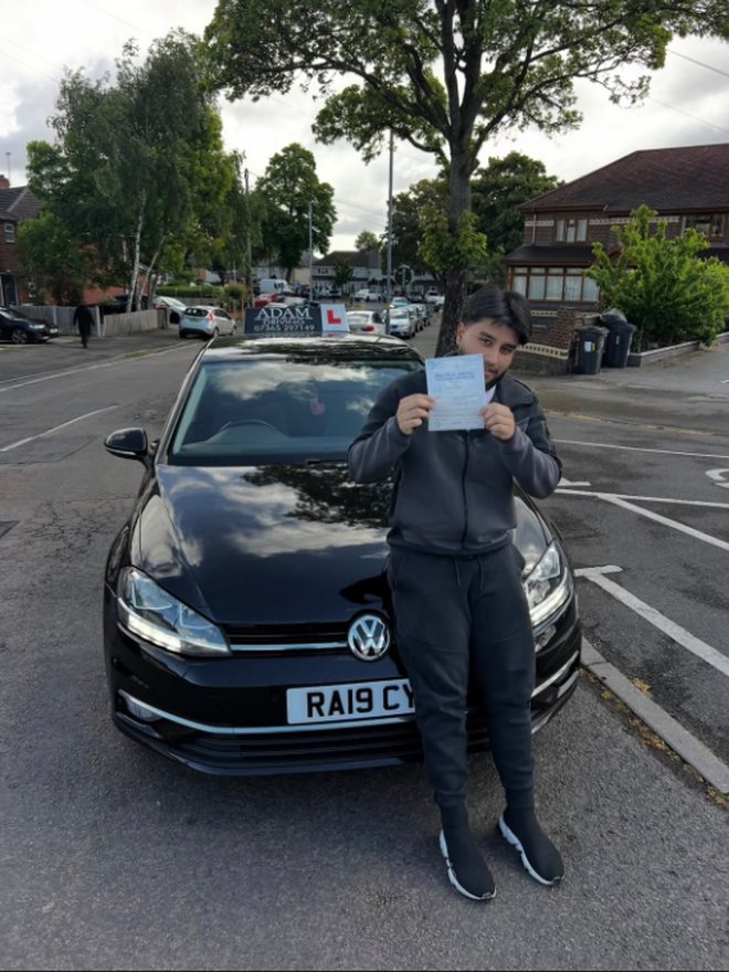 Student holding their driving test pass certificate beside the Adam Driving School car