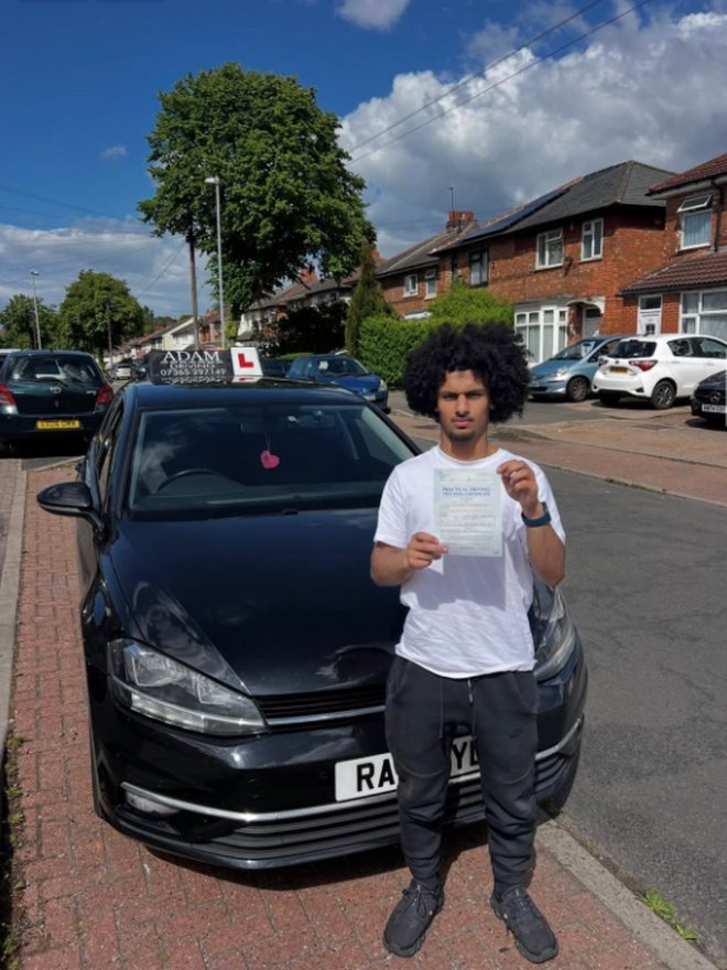 Student holding their driving test pass certificate beside the Adam Driving School car